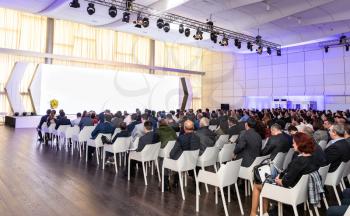 Audience at the conference hall, people looking at the screen