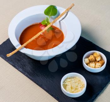 Tomato red soup with bread crumbs on the black plate