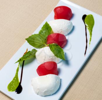 Beautiful ice cream balls with tomato on the white plate