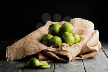 Green limes on brown bag on a table