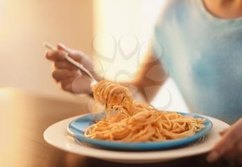Young woman eating tasty pasta at table, closeup�