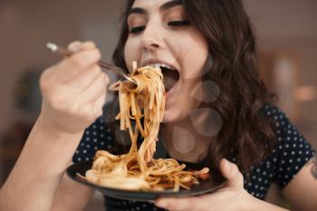 Young woman eating tasty pasta in cafe�