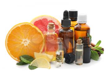 Bottles of citrus essential oil and fruits on white background�