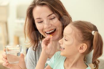 Little daughter giving pill to her mother at home�