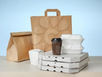 Different packages on table against color background. Food delivery service�