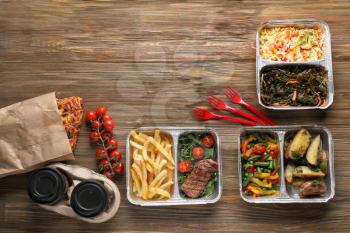 Different containers with delicious food on wooden table. Delivery service�