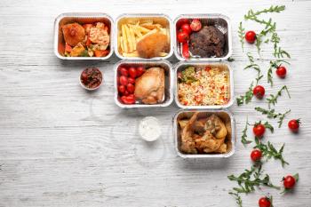 Containers with delicious food on wooden table. Delivery service�
