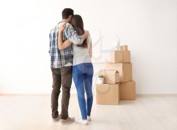Young couple hugging near boxes indoors. Moving into new house�