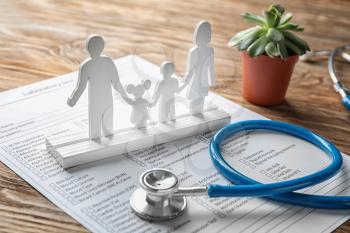 Composition with family figure and stethoscope on wooden table. Health care concept�