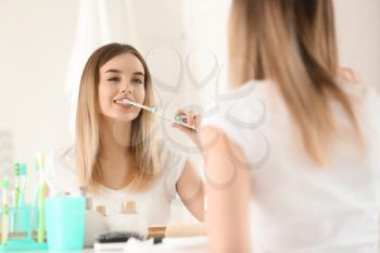 Beautiful young woman brushing her teeth in morning�