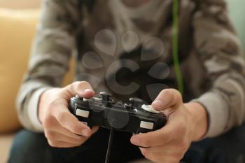 Teenager playing video games at home, closeup�