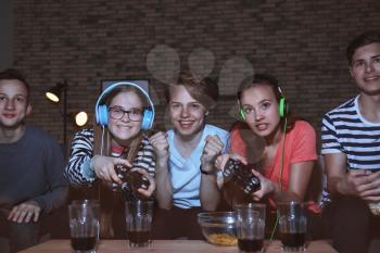 Teenagers playing video games at home late in the evening�