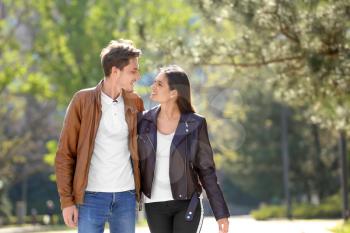 Happy young couple walking together in city park�