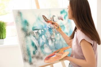 Female artist painting picture in workshop�