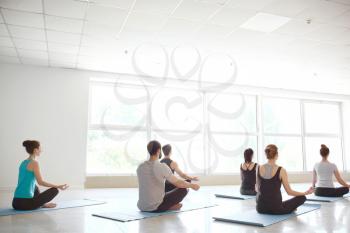 Group of people practicing yoga in gym�