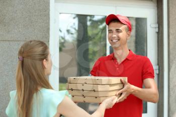 Young man giving pizza boxes to woman outdoors. Food delivery service�