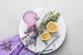 Wooden board with lavender lemonade in glass and ingredients on grey background�