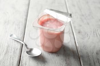 Plastic cup with yummy strawberry yogurt on wooden background�