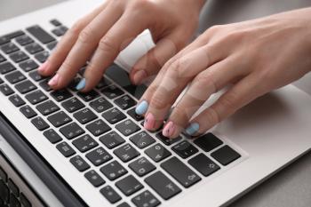 Woman with stylish color nails using laptop on table, closeup�