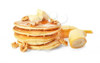 Tasty pancakes with sliced banana, butter and walnuts on white background�