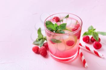 Glass of fresh raspberry mojito on color background�