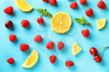 Composition with ripe aromatic raspberries, lemon slices and cherries on color background�