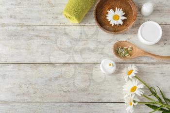 Composition with natural cosmetics and chamomile flowers on wooden background�