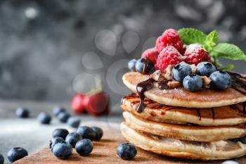 Tasty homemade pancakes with berries on wooden board, closeup�