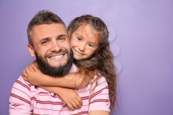 Little girl hugging her father on color background�