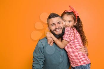 Little girl hugging her father on color background�