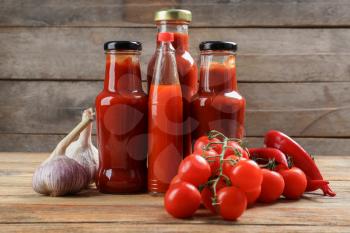 Bottles with tasty tomato sauces and on wooden table�