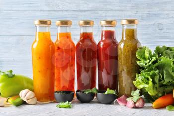 Bottles with different tasty sauces and vegetables on light table�
