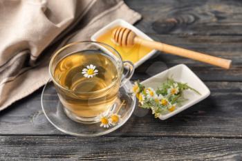 Cup of delicious camomile tea and honey on wooden table�