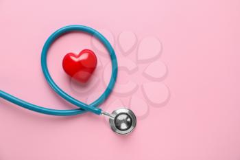 Medical stethoscope and red heart on color background. Cardiology concept�