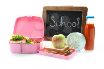 Appetizing food in lunch box and small chalkboard with word SCHOOL on white background�