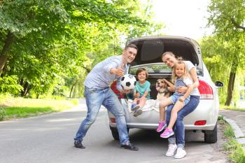 Happy family with cute dog near car outdoors�