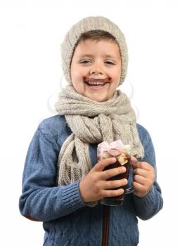 Funny little boy in warm clothes with glass cup of hot chocolate on white background�