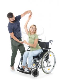 Beautiful woman in wheelchair with man dancing on white background�