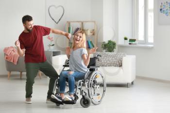 Beautiful woman in wheelchair with man dancing at home�
