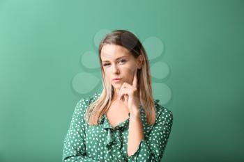 Suspicious young woman on color background�