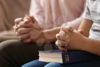 Little boy and his mother praying at home, closeup 