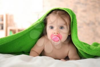 Cute little baby with soft towel on bed at home�