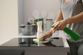 Woman cleaning stove in kitchen�