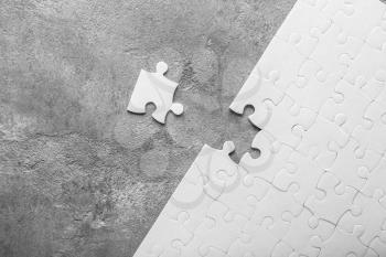 White jigsaw puzzle with piece on grey background�