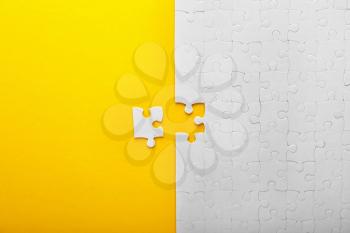 White jigsaw puzzle with piece on color background�