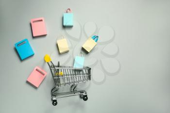 Shopping cart with small bags on grey background�