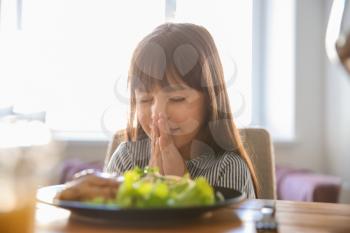 Little girl praying before meal at home�