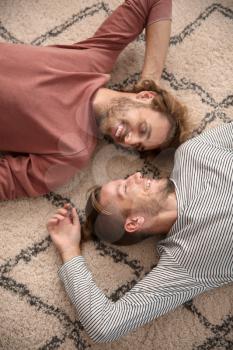 Young LGBT couple lying on floor�