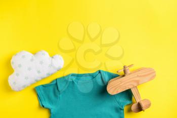 Baby clothes and toys on color background, top view�