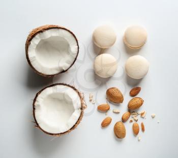 Fresh tasty macaroons with cut coconut and almonds on white background�